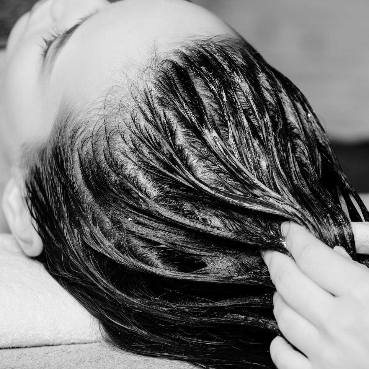 Person receiving a hair treatment with product being applied to hair strands.