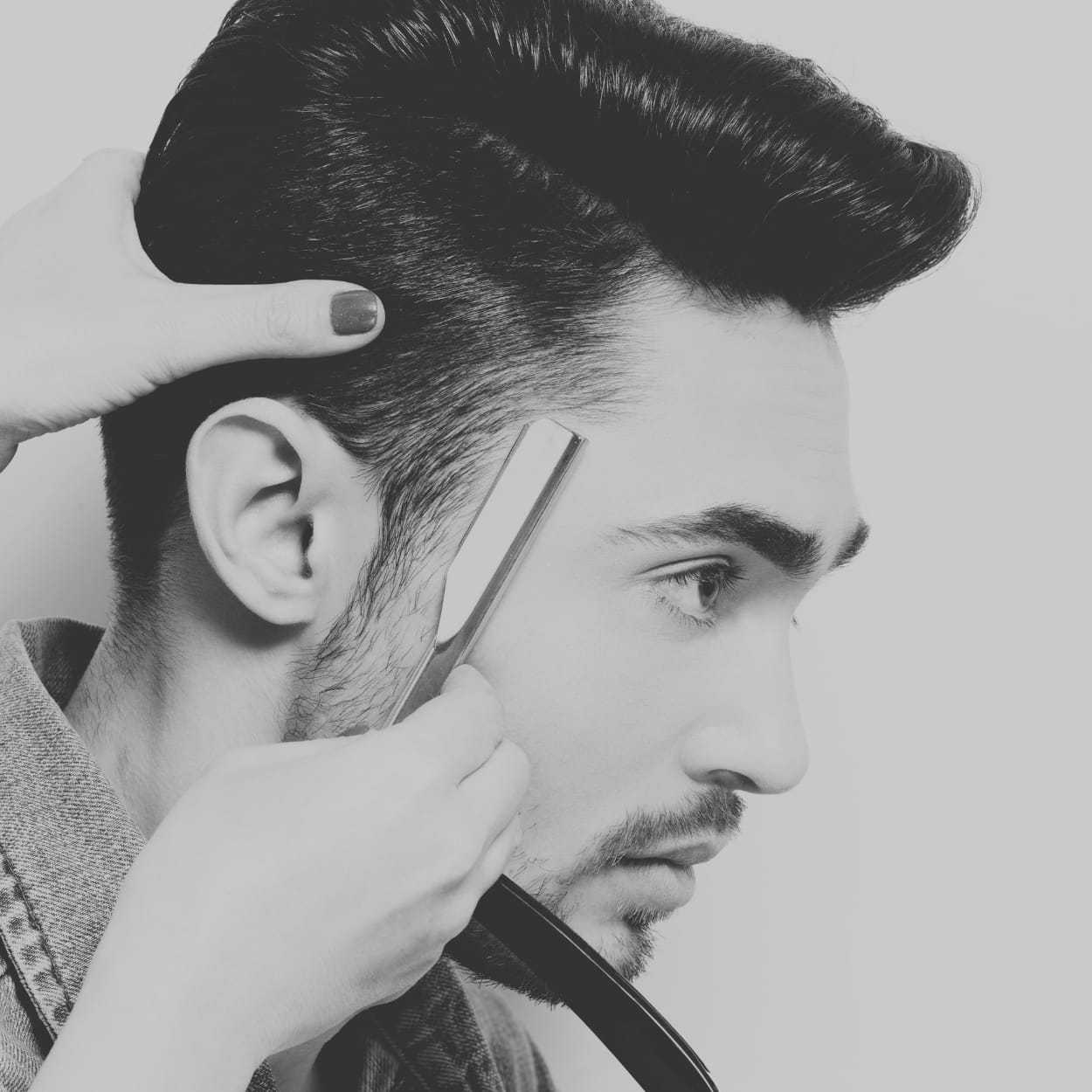 Man getting a haircut with a straight razor, barber adjusting his head for precision.