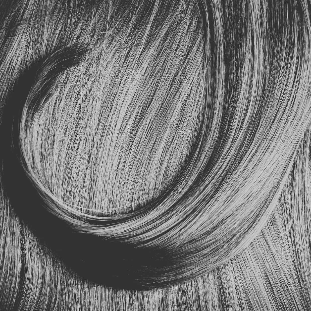 Close-up of wavy, smooth, and shiny gray hair flowing in a curved pattern.