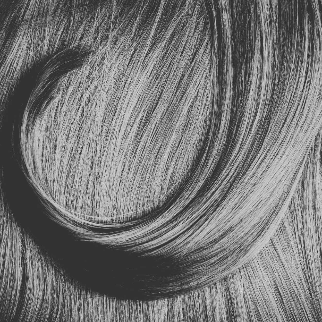 Close-up of wavy, smooth, and shiny gray hair flowing in a curved pattern.