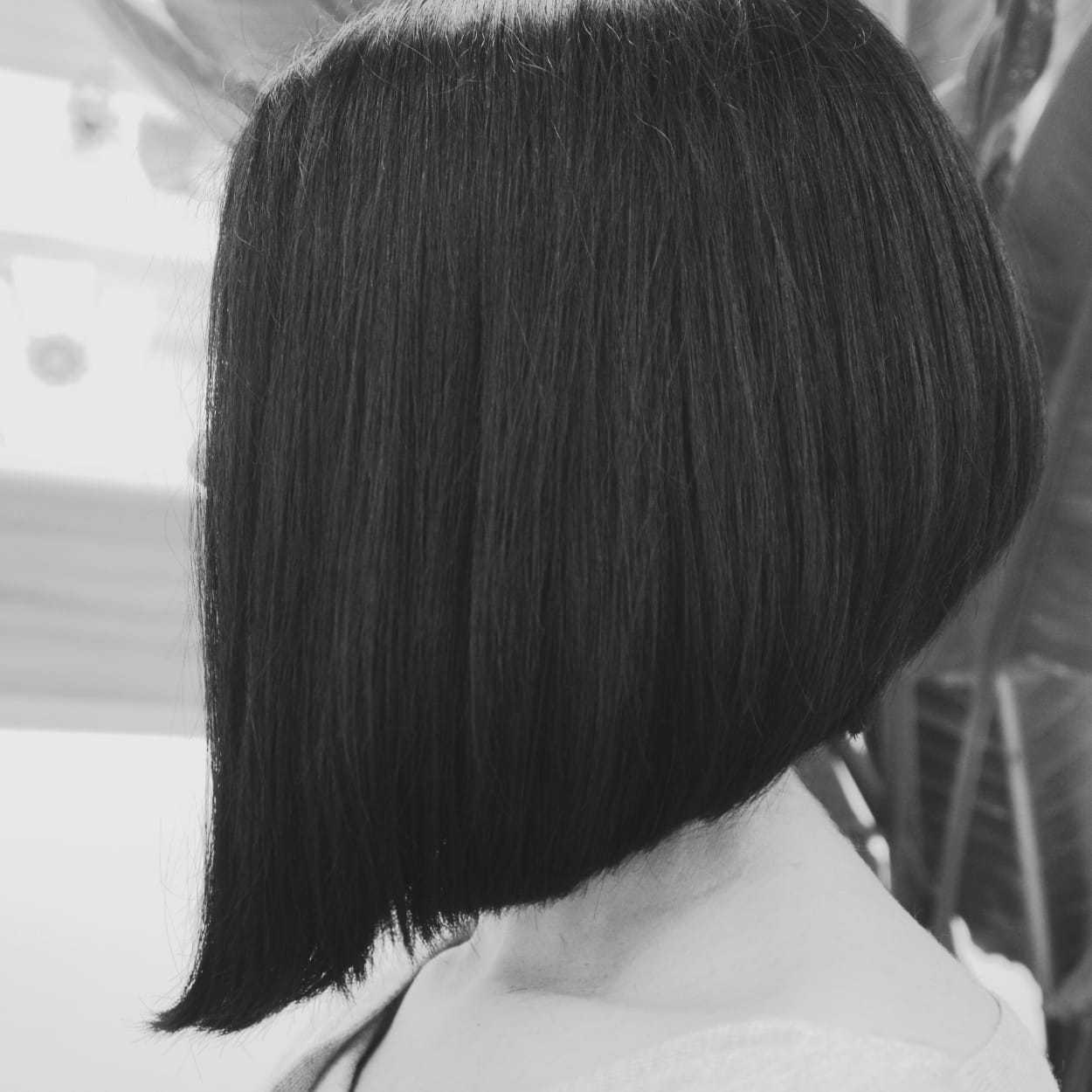 Side view of a person with a sleek, chin-length bob haircut in a black and white photo.