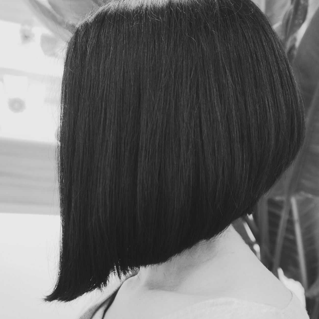 Side view of a person with a sleek, chin-length bob haircut in a black and white photo.